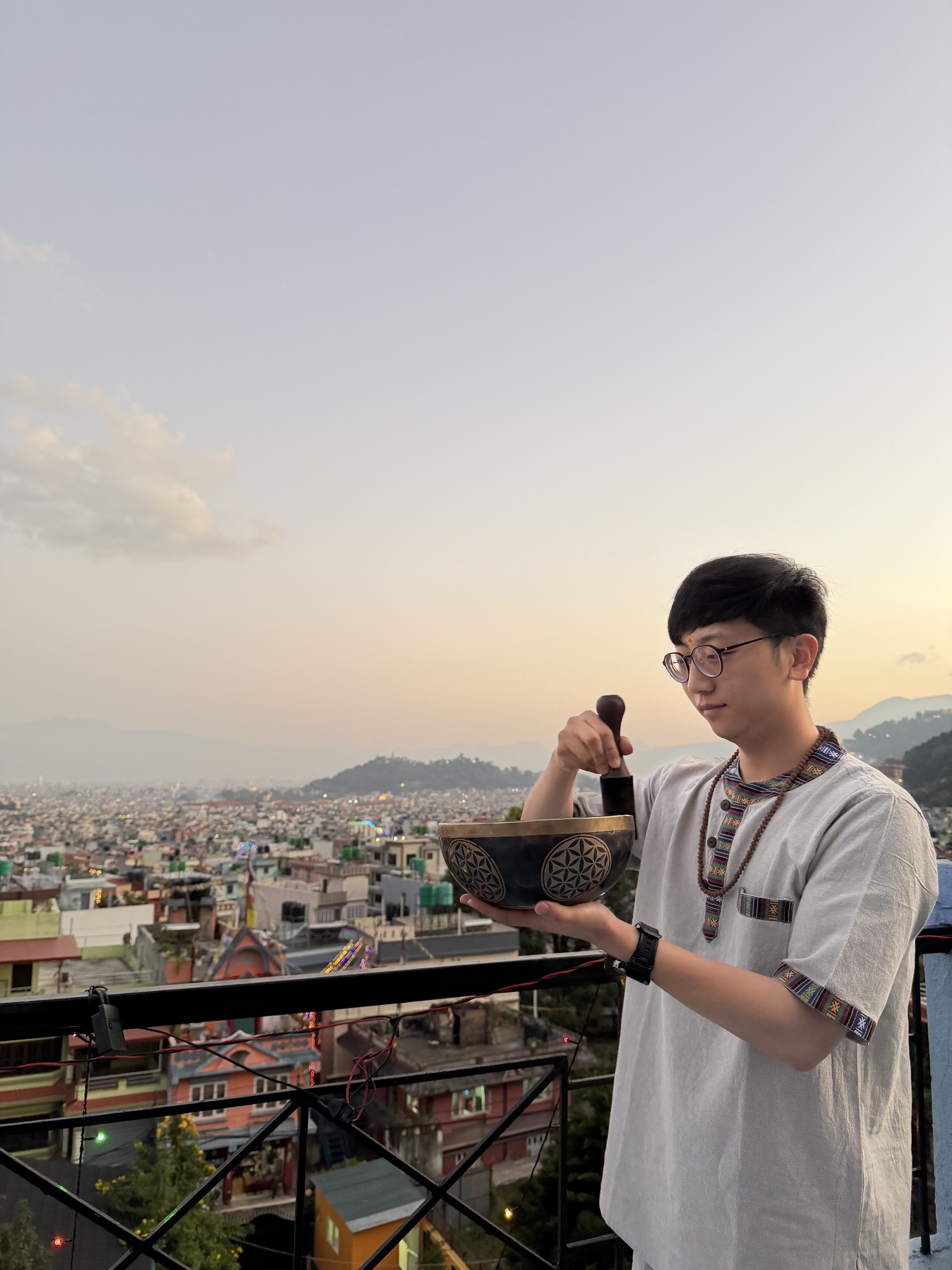 Kirk 在尼泊爾持頌缽，身後是加德滿都與柔和天空